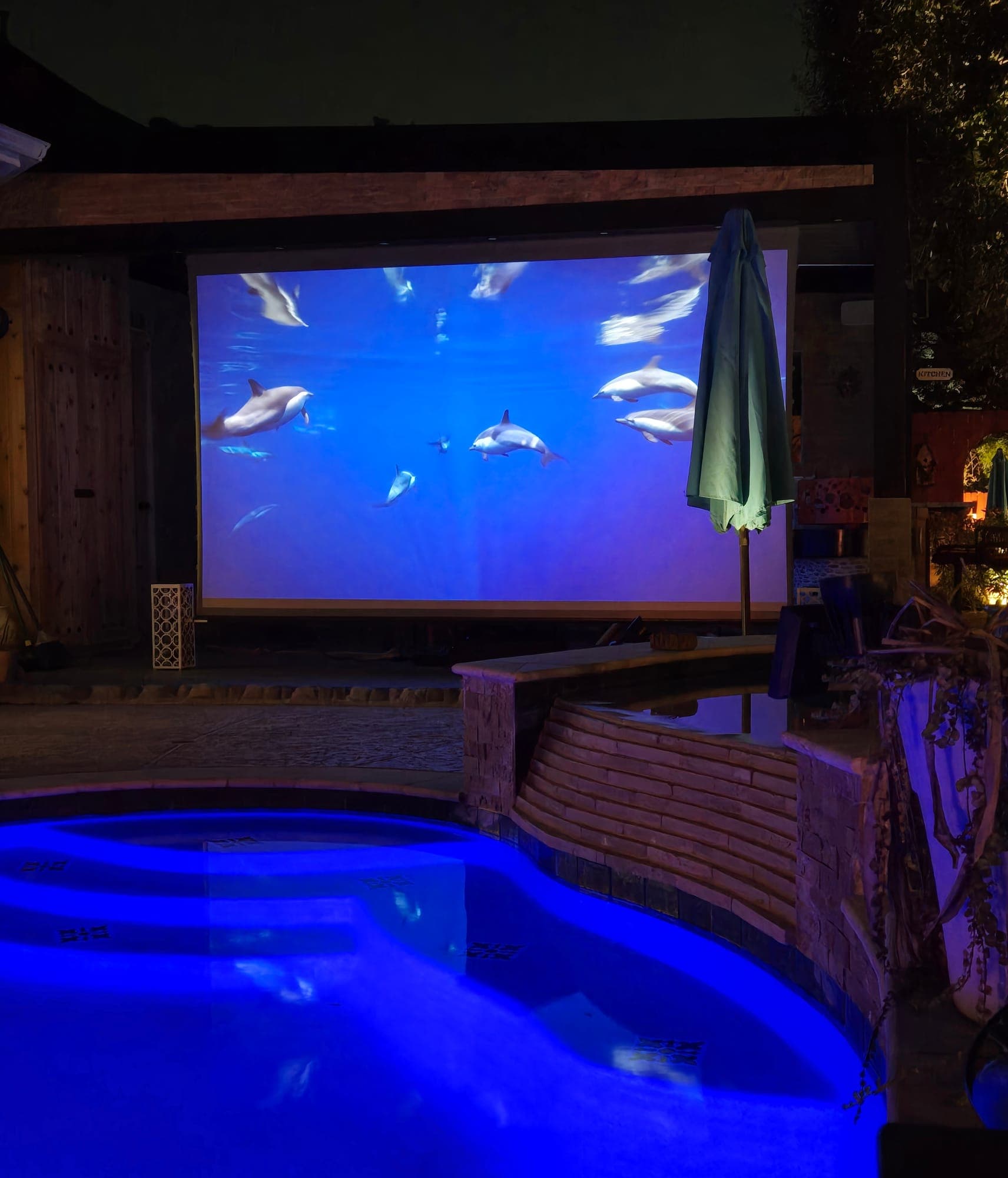 Outdoor poolside theater screen lit blue at night
