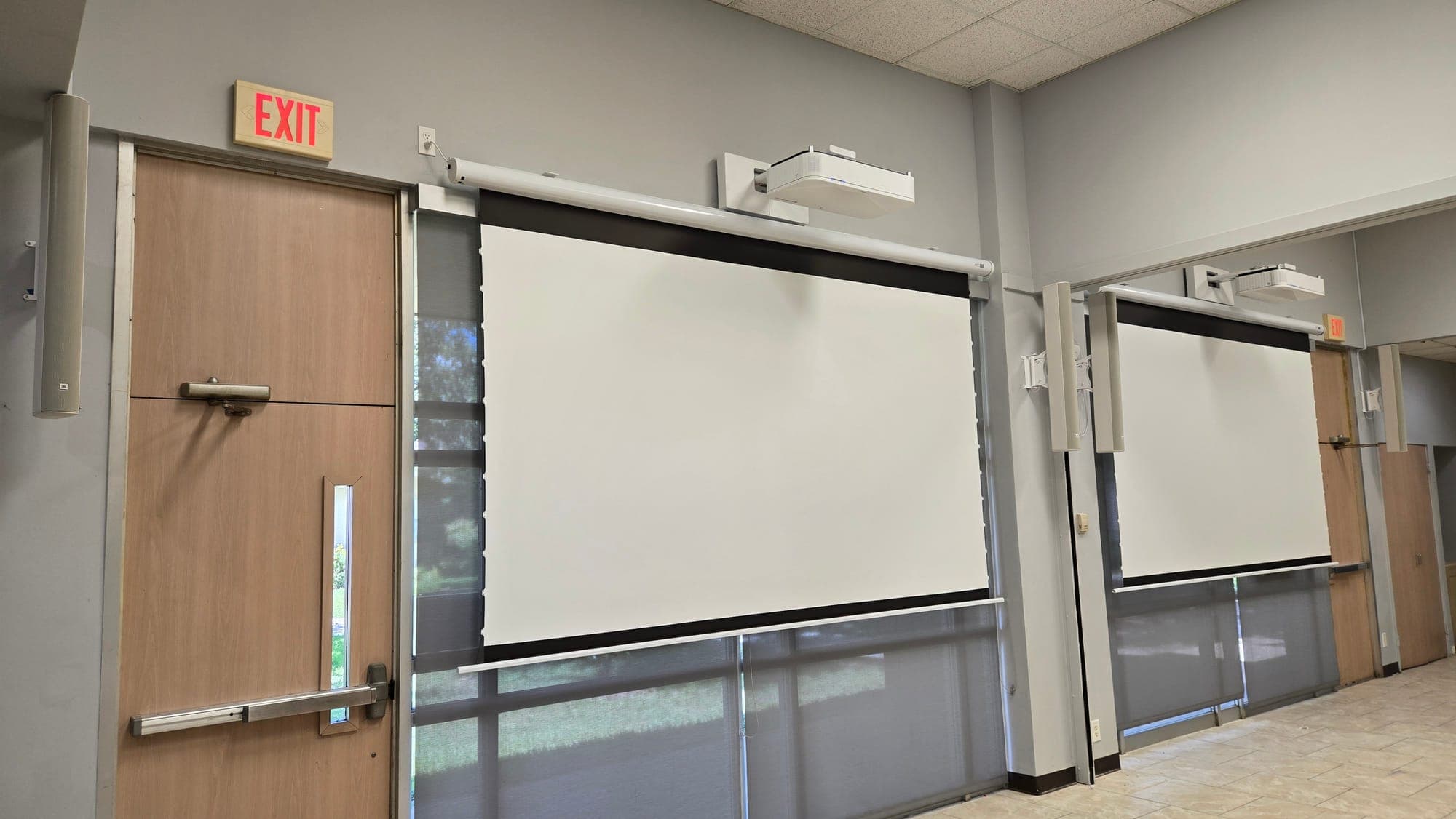Dual motorized projection screens in a commercial meeting room