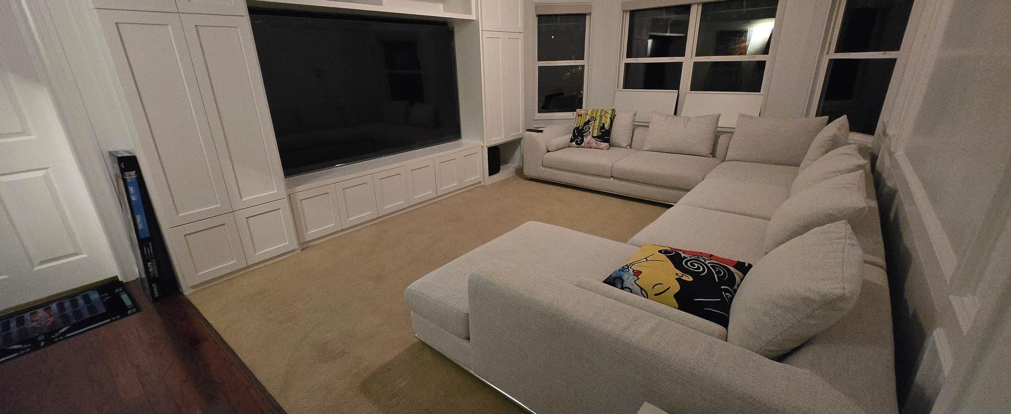 Family media room with built-in cabinetry, a large TV, and a sectional sofa