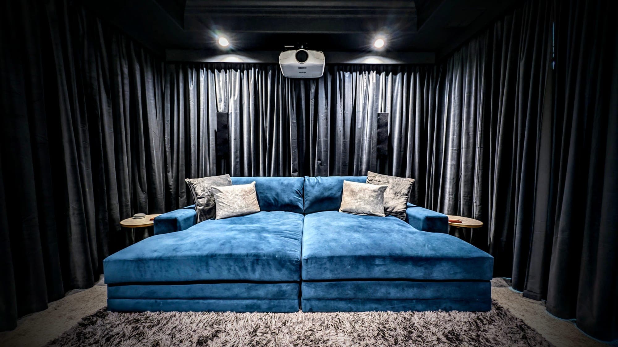 Home theater lounge with a blue velvet daybed and ceiling projector