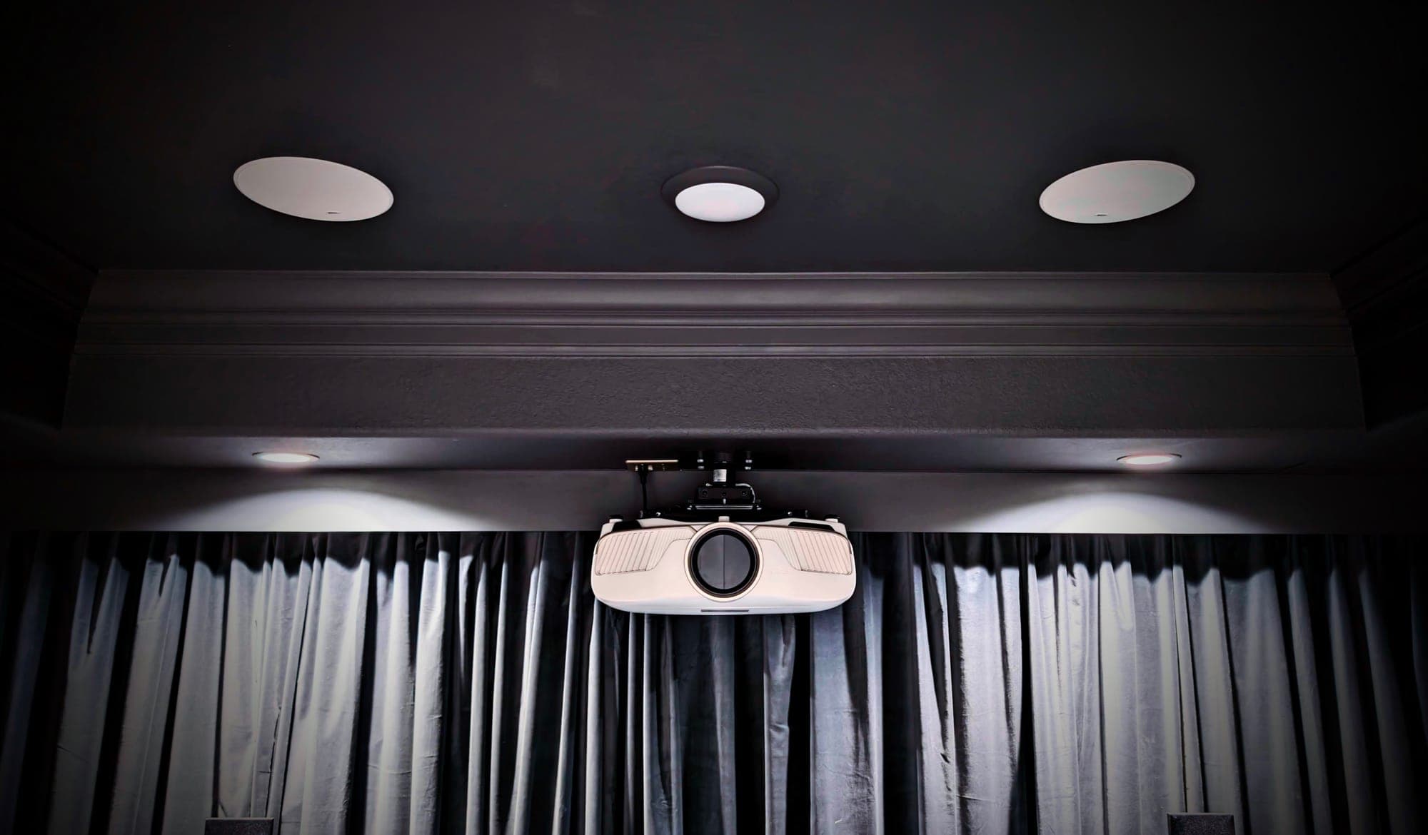 In-ceiling speakers and a ceiling-mounted projector in a cinema room