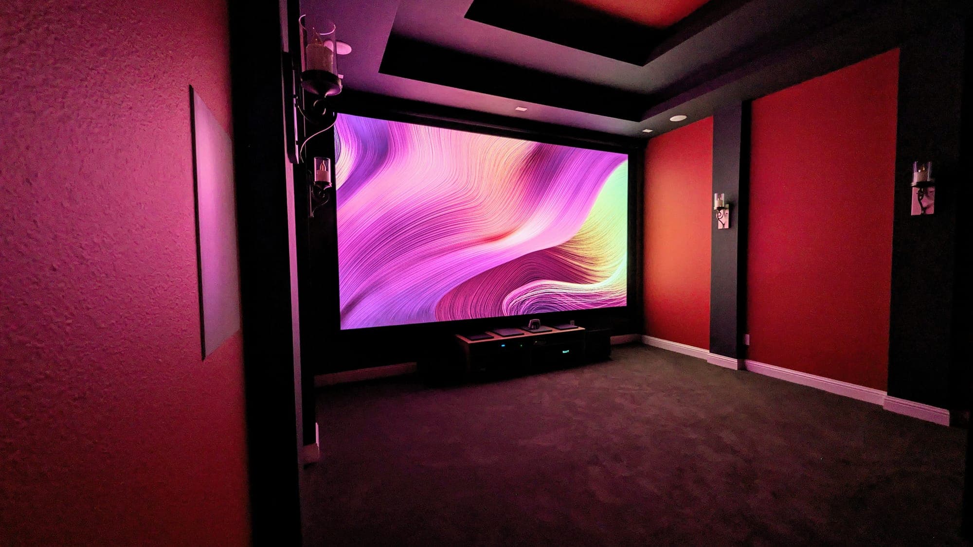 Red home theater with ambient cove lighting and a wide projection screen